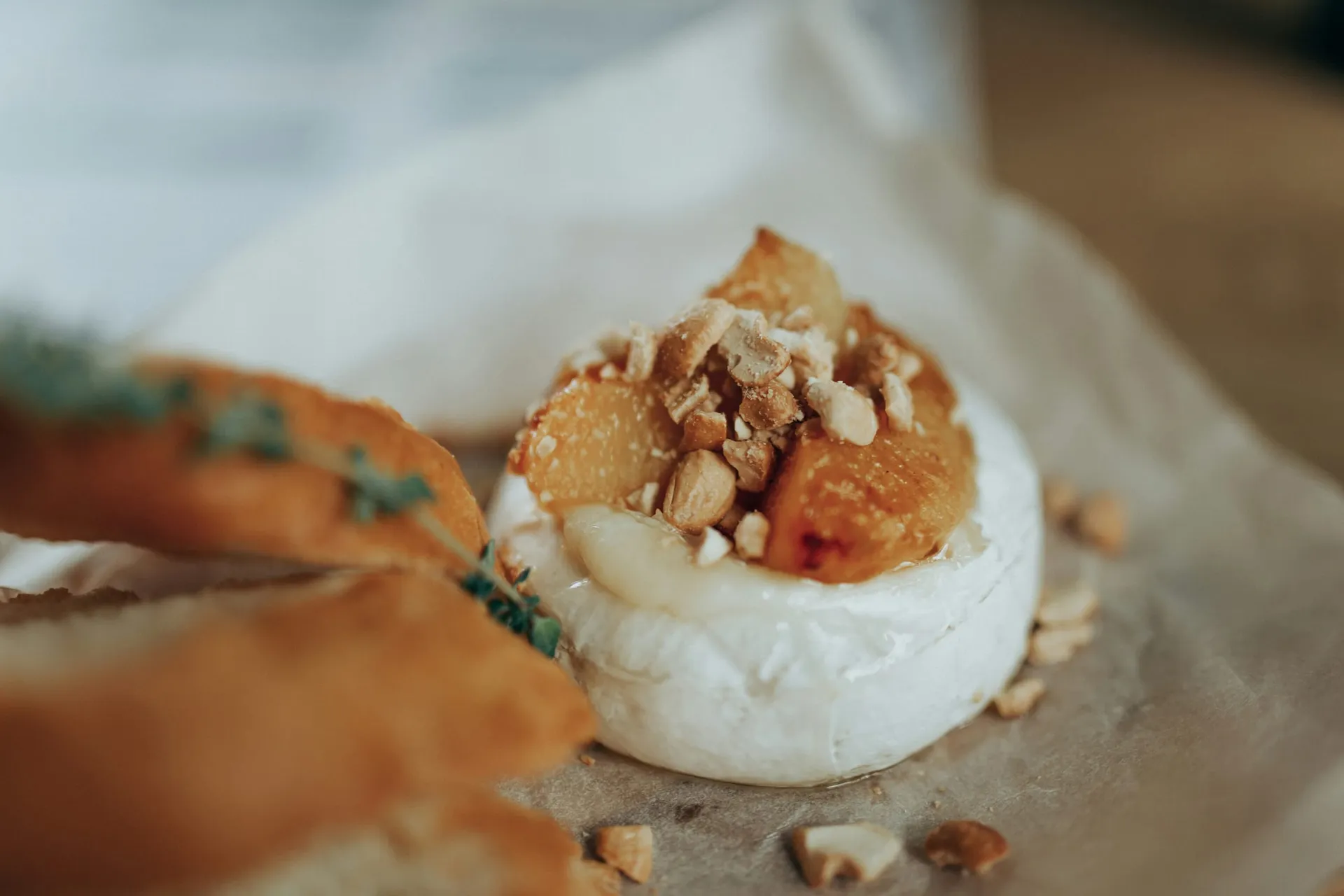 Warme zachte kaas uit de oven met gebakken fruit en nootjes, naast geroosterd brood