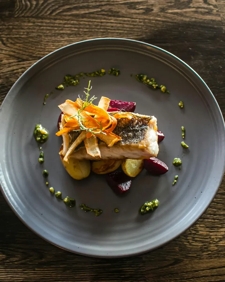 Gebakken zeebaars met knapperig vel op krieltjes en rode biet, met toefjes pesto