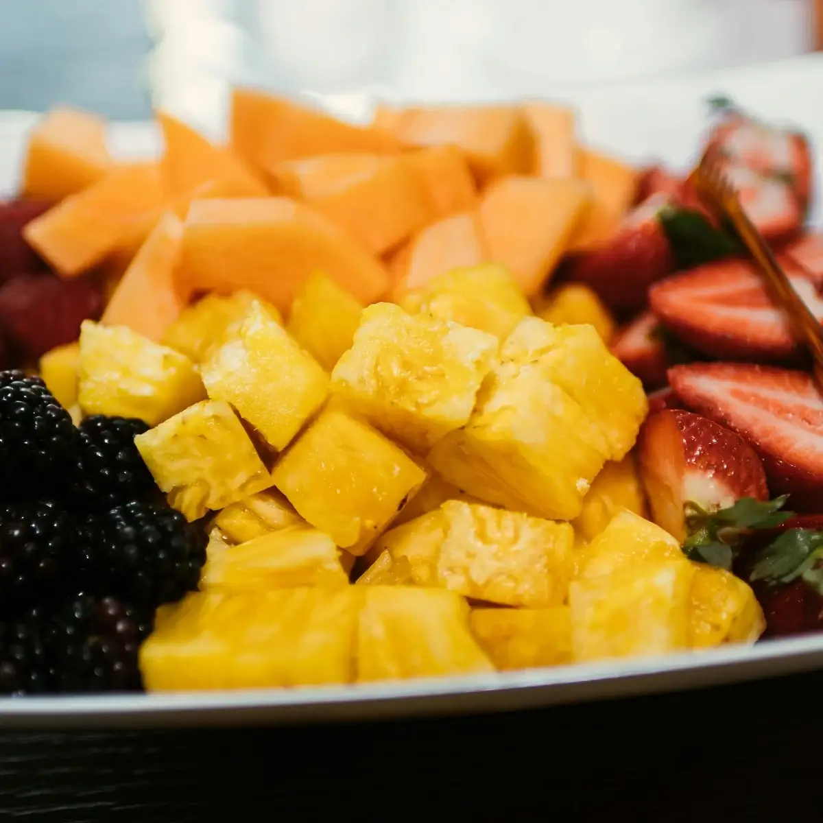 Fruitschaal met meloen, ananas, aardbeien en bramen