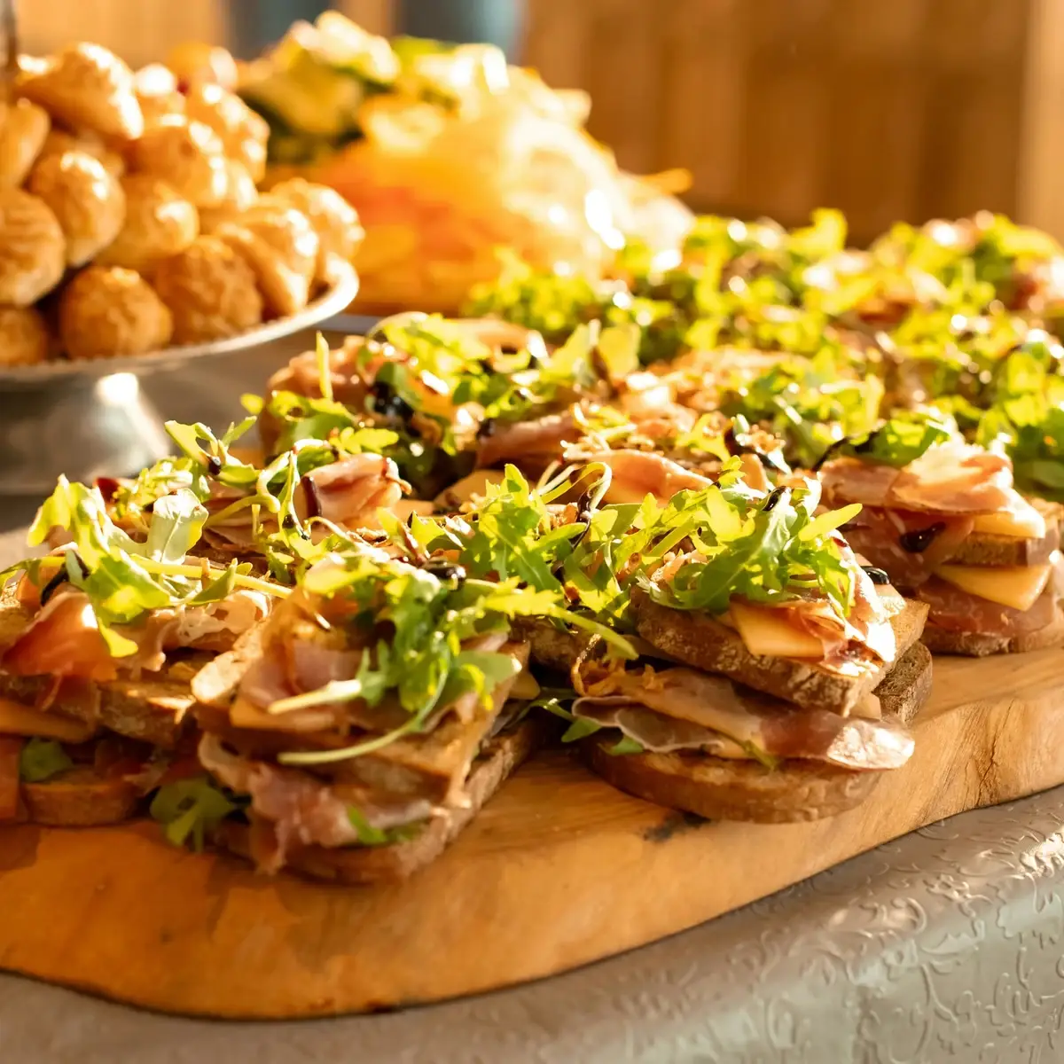 Open toastjes met ham, kaas en rucola op een houten plank